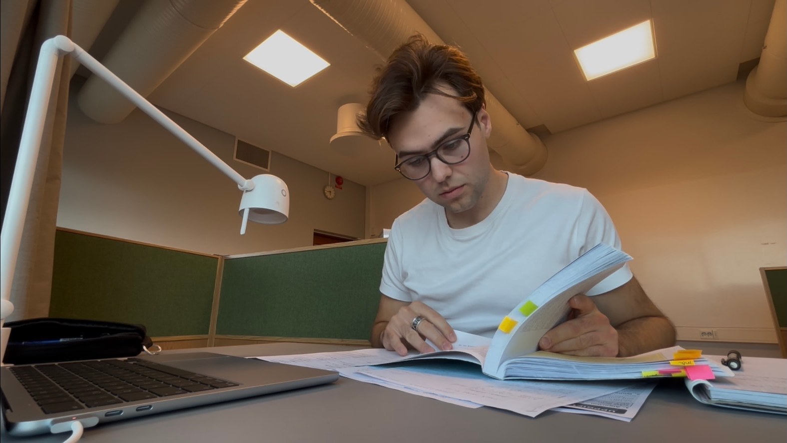 Mauritz pluggar fokuserat med bok och anteckningar vid ett skrivbord